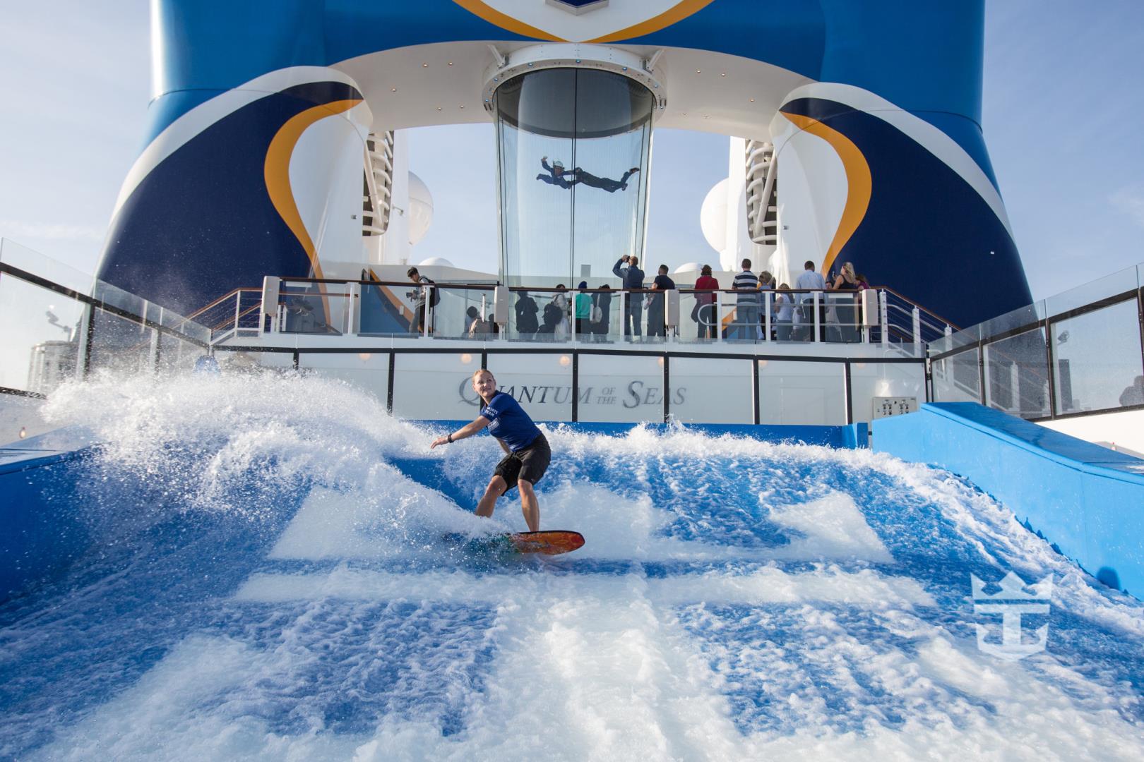 View of woman surfing on the FlowRider with skydiving simulation on iFly in the background